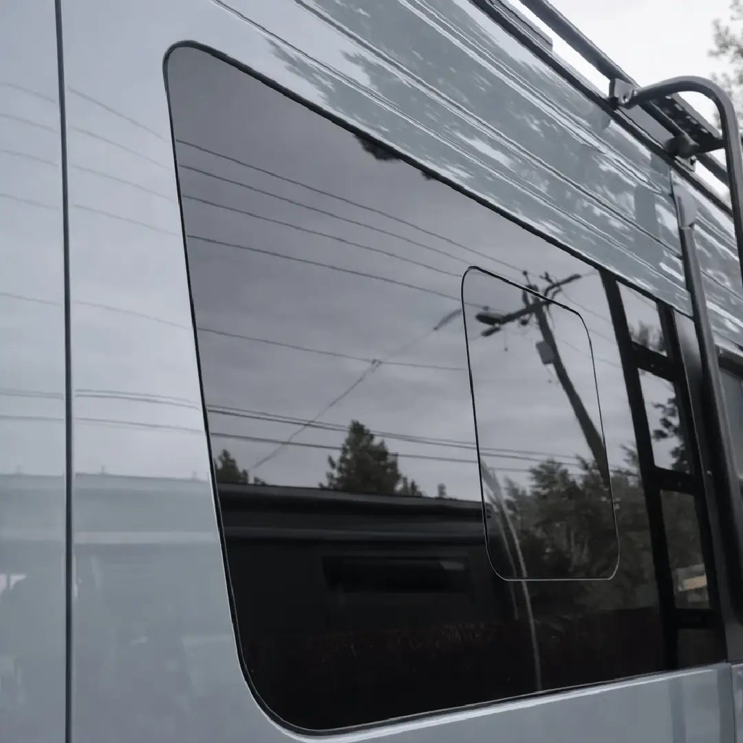 Angled exterior view of the Glacier View Sprinter driver-side front flush sliding window showing its flush fit and closed vent panel.