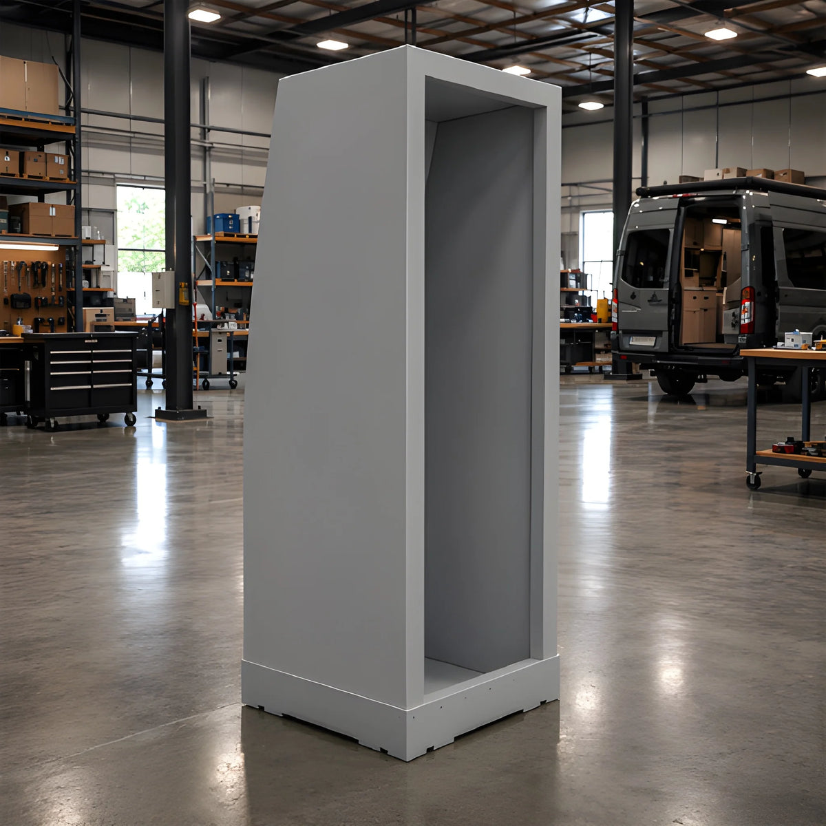 Gray Vankea XS 25-inch aluminum shower enclosure standing in a van conversion workshop, with its open front and pan visible.