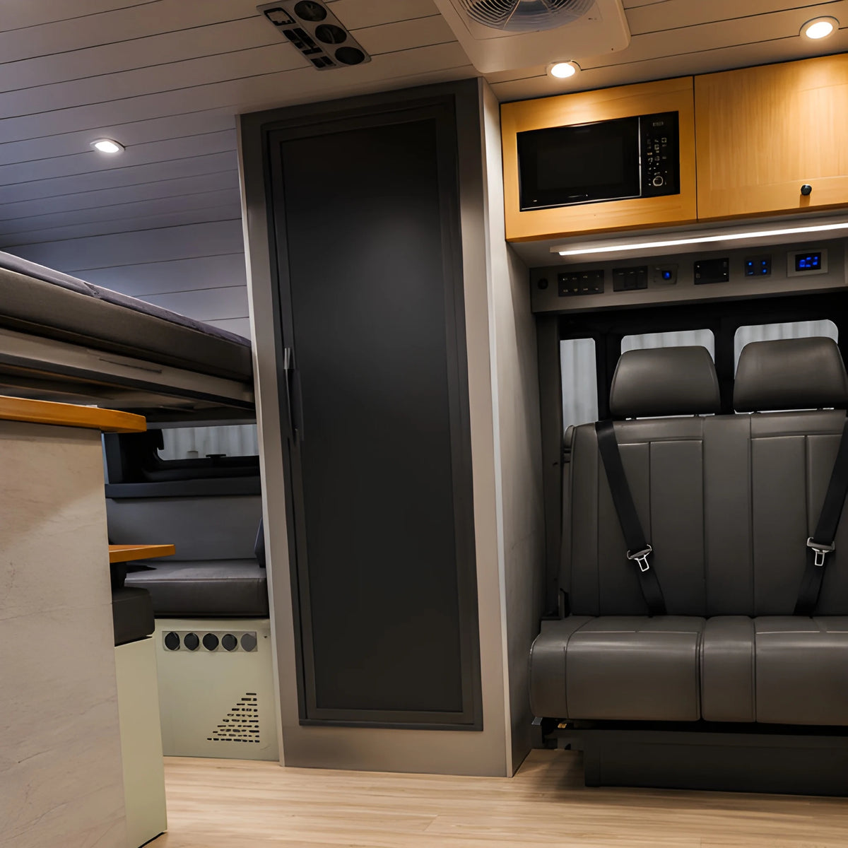 Vankea XS aluminum shower installation example inside a camper van, with a closed dark door beside passenger seating and cabinetry.