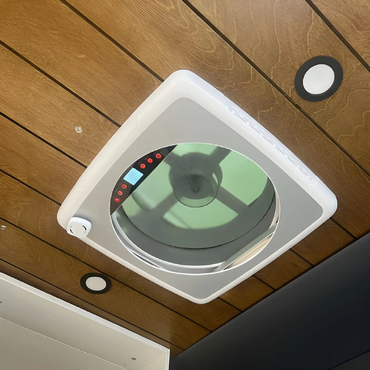 Angled interior view of the Cryonex 12V roof fan installed in a wood camper van ceiling, with fan blades and controls visible.