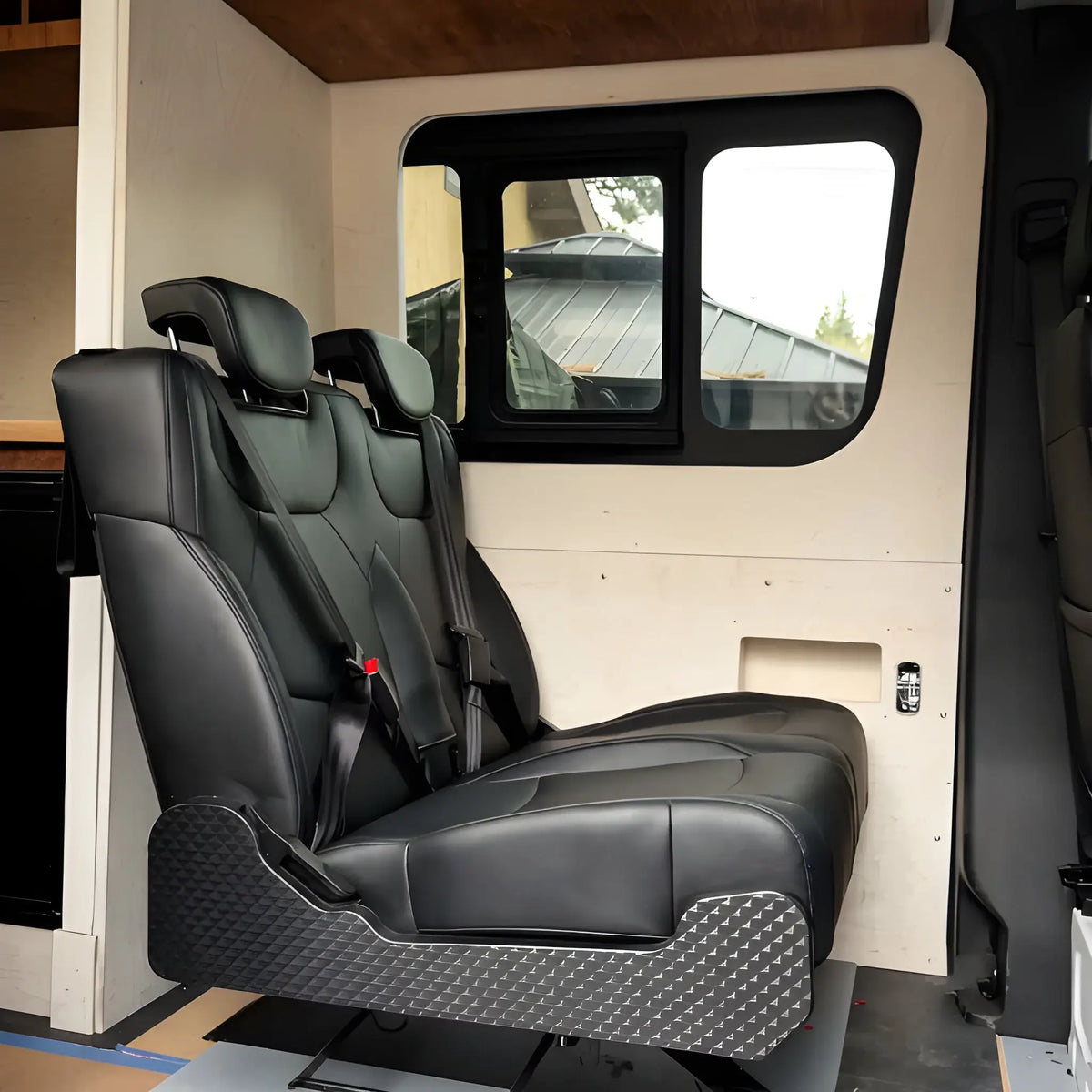 Side view of the NovaLux Duo RS double seat installed inside a camper van beneath a sliding window.