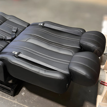 Close-up of the NovaLux Classic double seat in its flat reclined position, with headrests and shoulder belts visible.
