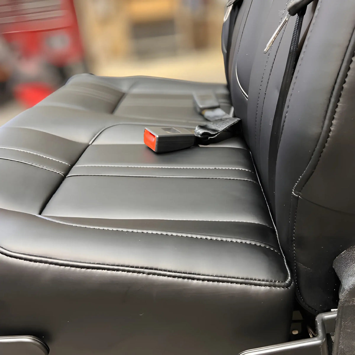 Detail of the NovaLux Classic double van seat cushion, upholstery stitching and red seat belt buckle.