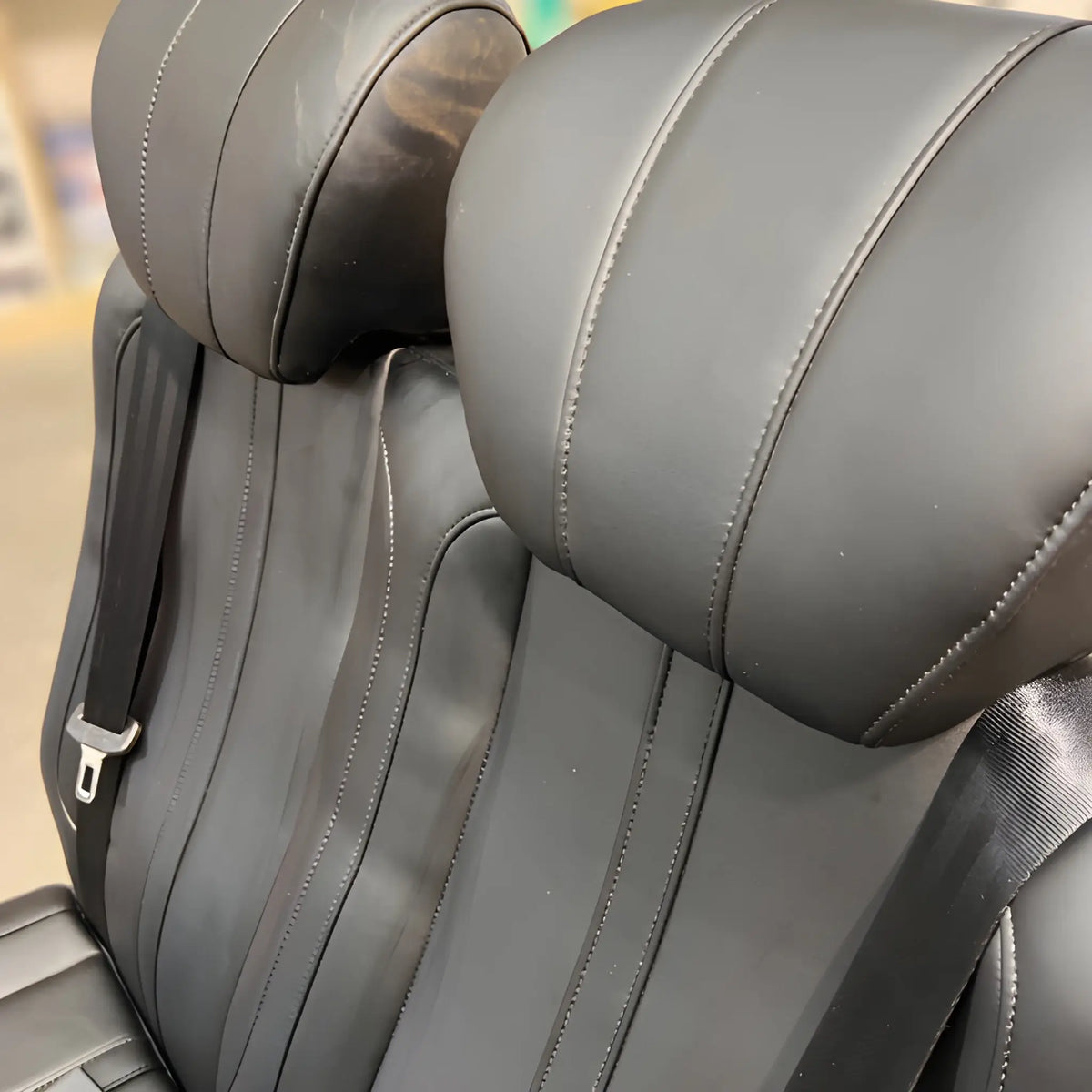 Close-up of the NovaLux Classic double van seat headrests, stitched backrests and integrated shoulder belts.