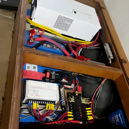 VanTrix 12V 600Ah LiFePO4 battery installed in a camper van electrical compartment with cables, fuses and power equipment.