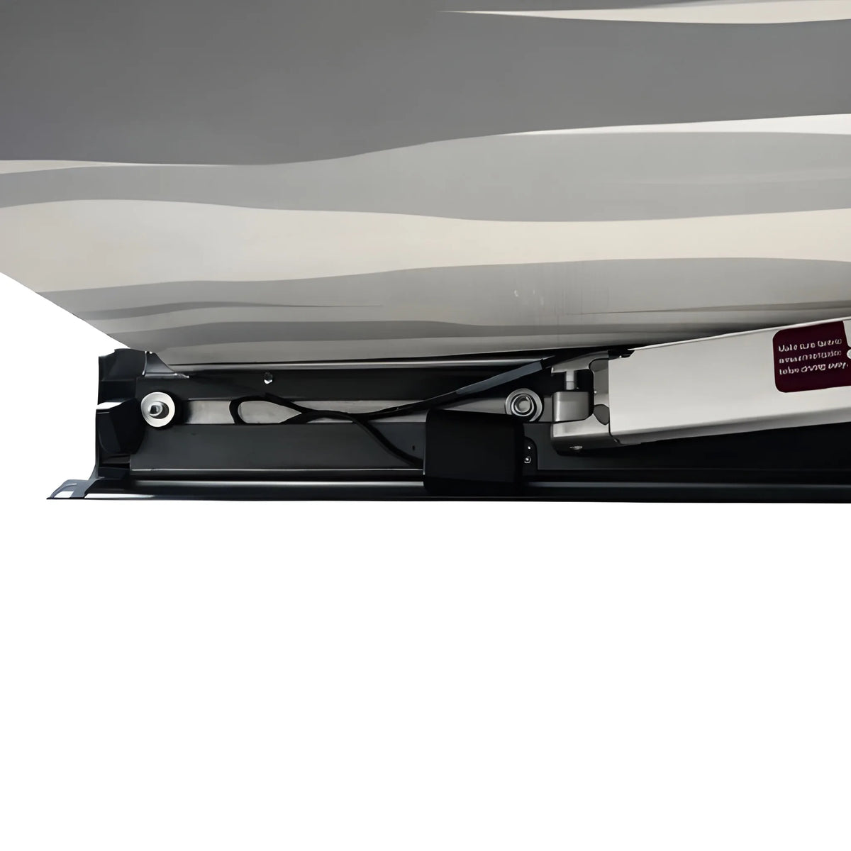 Close-up beneath the Vantrix electric awning showing the folding support arm, wiring and cassette under the patterned canopy.