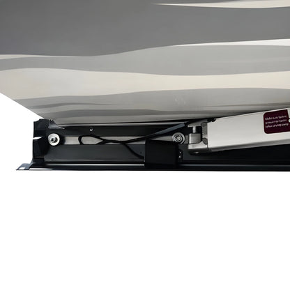 Close-up beneath the Vantrix electric awning showing the folding support arm, wiring and cassette under the patterned canopy.